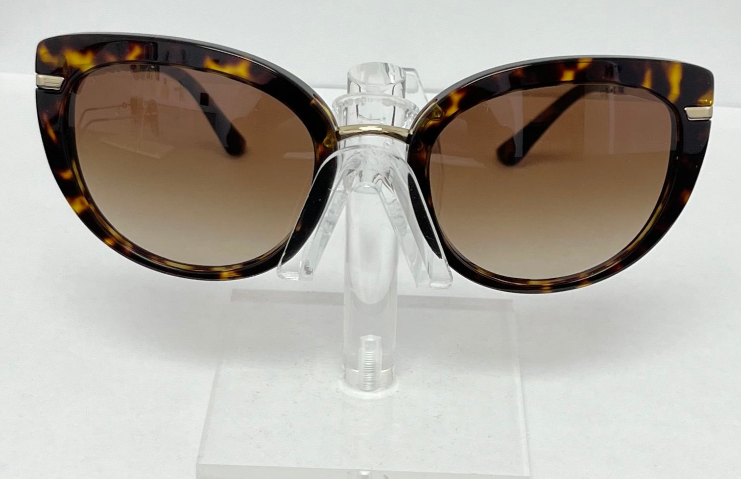 Tortoiseshell sunglasses on a clear stand against a white background
