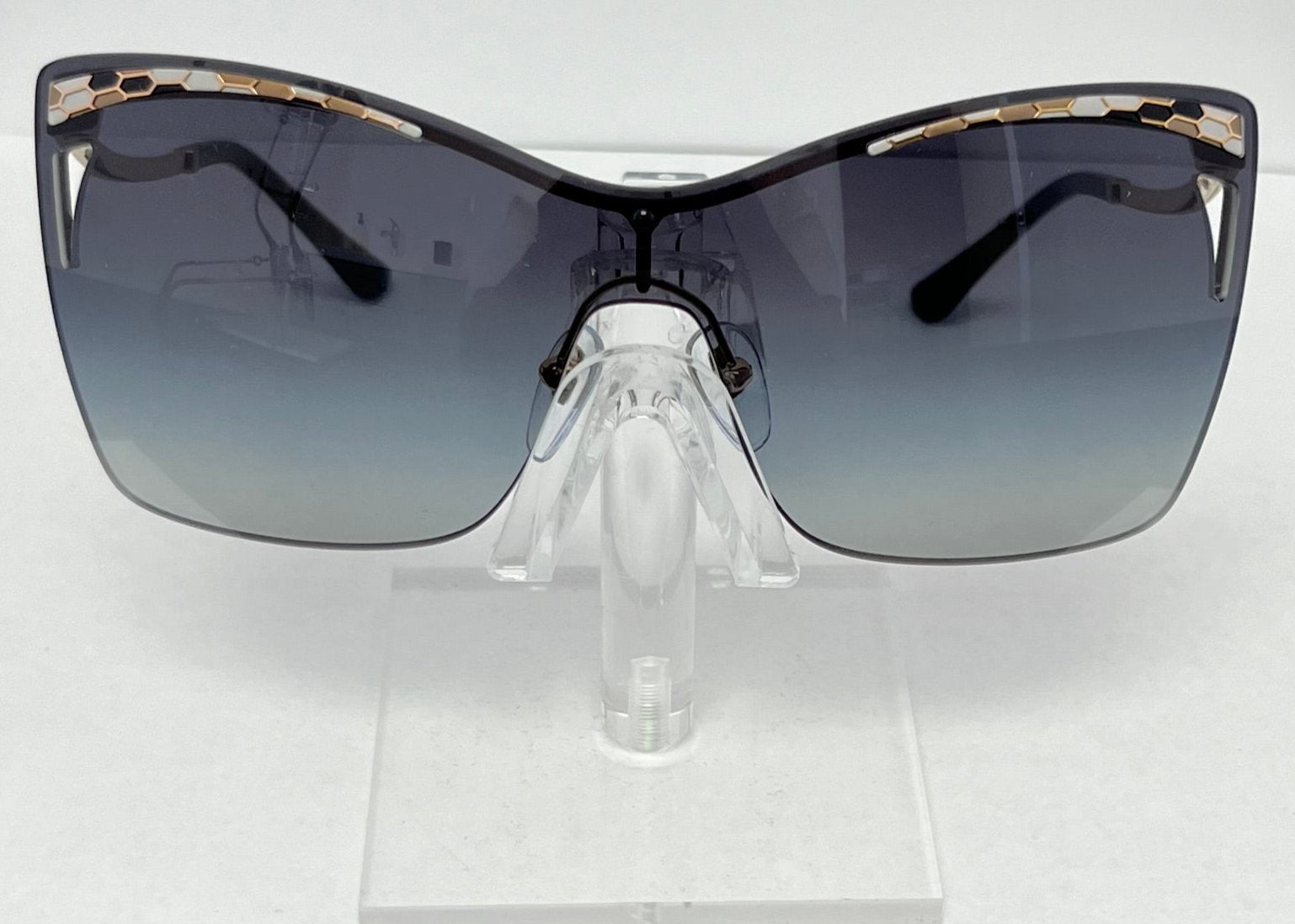 Sunglasses with a gradient lens on a clear stand against a white background