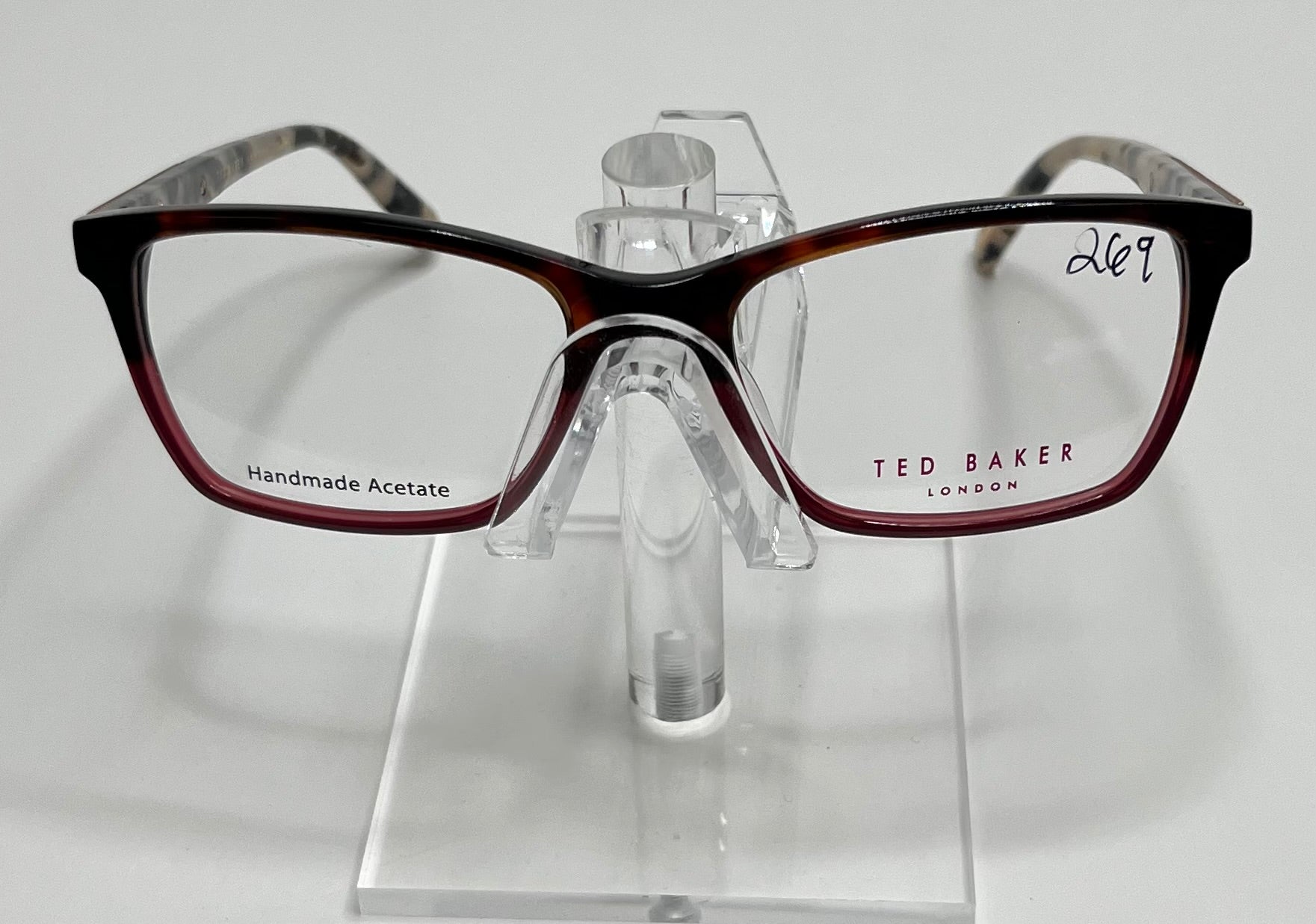 A pair of Ted Baker TPW006 ladies eyeglass frame in tortoise and blue color, displayed on a stand.