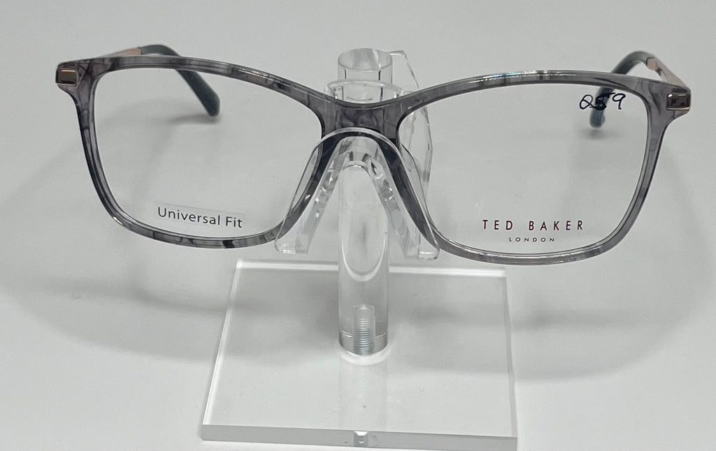 A pair of Ted Baker eyeglasses with a gray plastic frame, displayed on a stand.