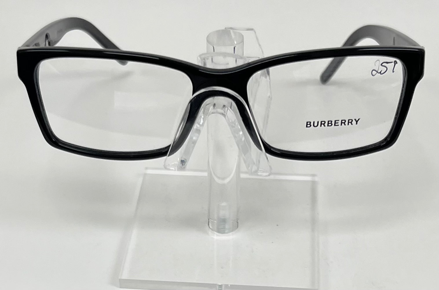 Black Burberry eyeglasses on a clear stand against a white background