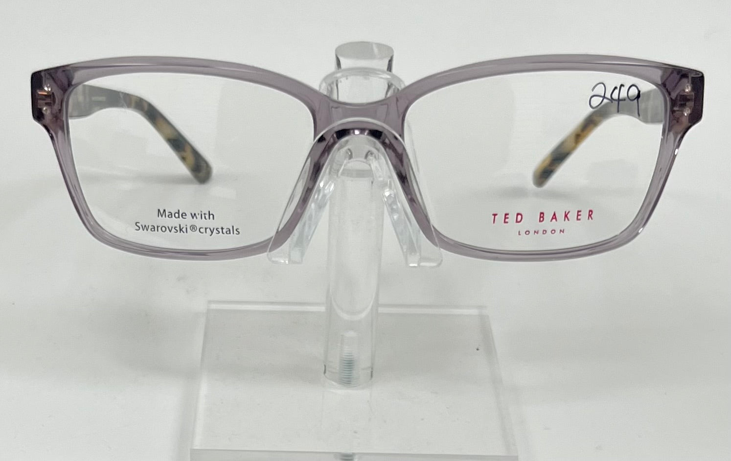 Gray eyeglasses on a stand with 'Ted Baker London' branding on a white background
